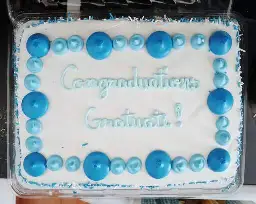 A white sheet cake with the text "Congraduations Gratuate!" written on it in blue icing
