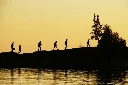 Cute silhouette of friends hiking out to a sunset bathed picnic by the lighthouse