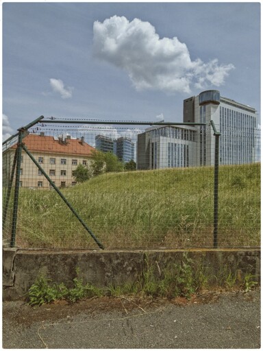 A cityscape trapped inside a barbed wire fence. 