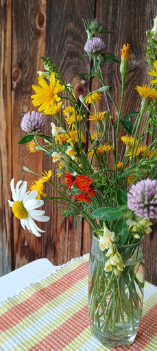 A colorful bouquet of mixed wildflowers in a glass vase.