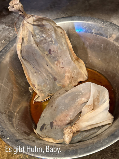 Two sacks filled with cooked chicken, thyme and cloves, dripping with Pedro Ximénez sherry, right before pouring the sherry into an Ale. Caption: "There will be chicken, baby" (in German).