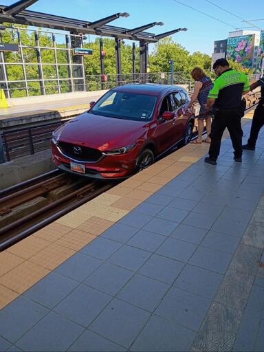 A red car on the rail track in a station